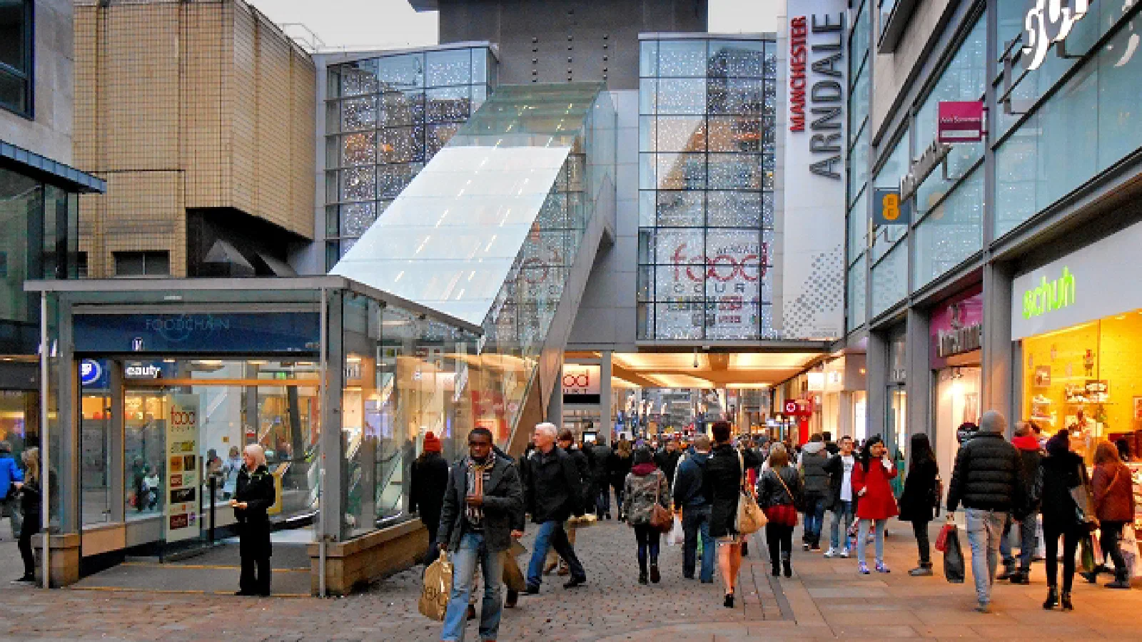 Crowds shop in an open-air mall under glass structures and festive lights. — Arndale Food Market, Manchester