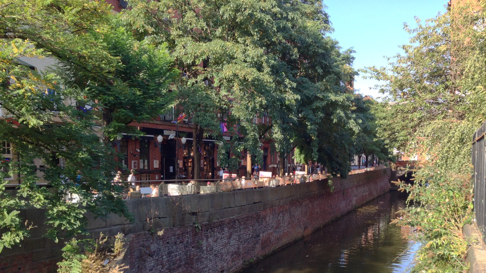 A sunny day on a canal lined with trees and brick walls. — Canal Street, Manchester