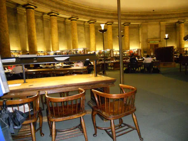 Wooden chairs at library tables under warm lighting. — Central Library Interior, Manchester
