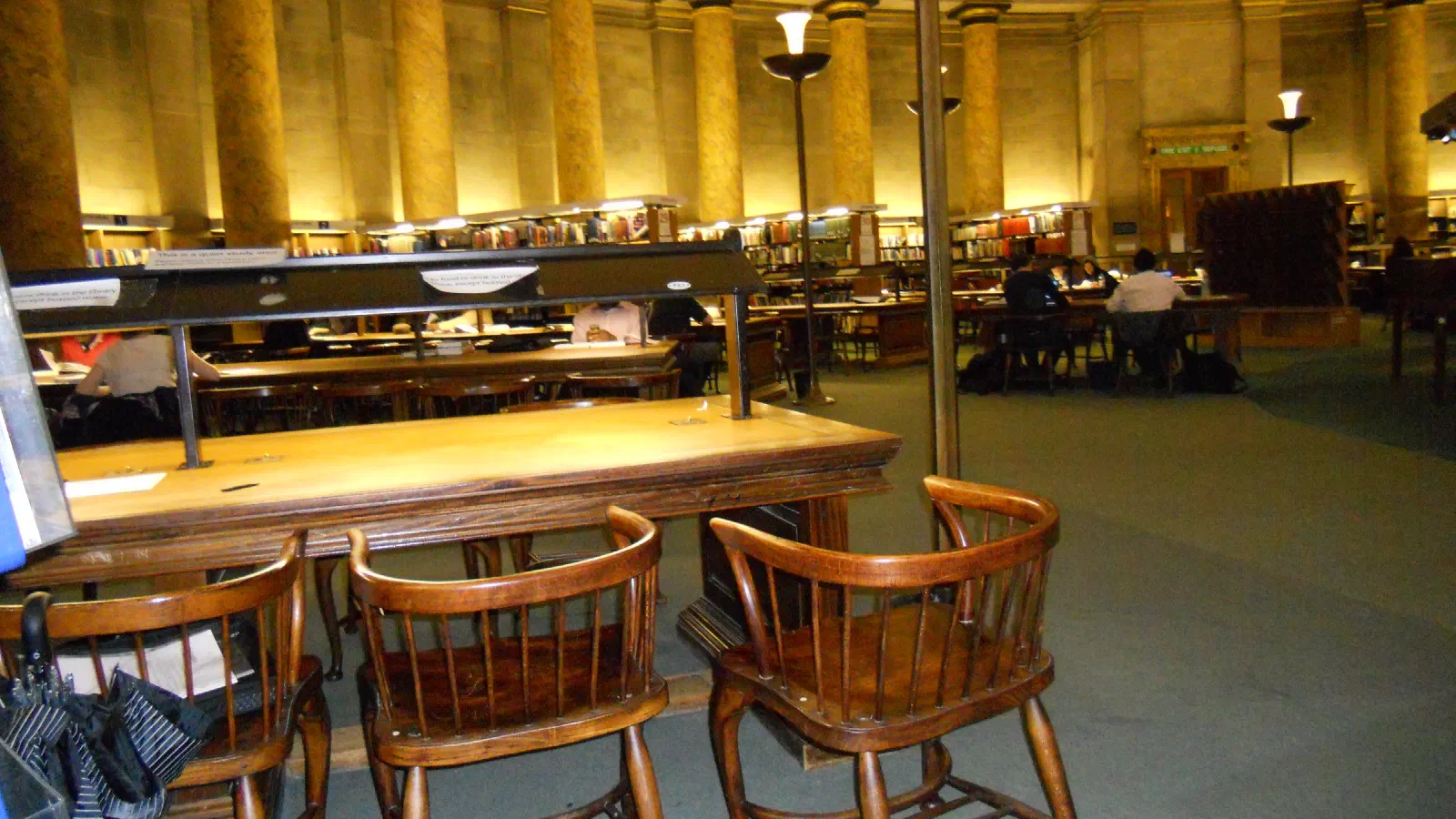 Wooden chairs at library tables under warm lighting. — Central Library Interior, Manchester