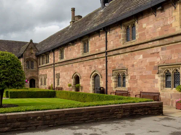 Stone building courtyard features well-manicured garden under cloudy sky. — Chetham’s Library, Manchester