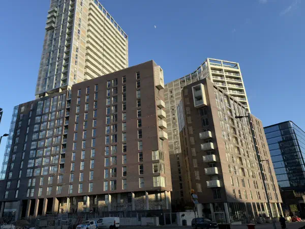 Tall brick apartment buildings under a clear blue sky on a sunny day. — Greengate, Manchester
