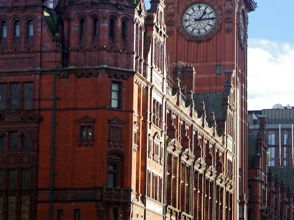 Red brick building stands tall against a clear blue sky with clock tower and green dome under bright sunlight. — Kimpton Clocktower Hotel (The Refuge), Manchester
