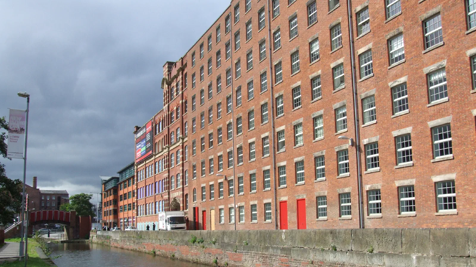 Red brick building beside canal under gray sky. — Murrays' Mills, Manchester