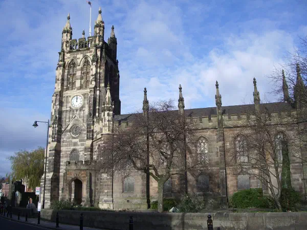 Stone church with clock tower, bare trees, blue sky. — St Mary’s Church & Staircase, Manchester